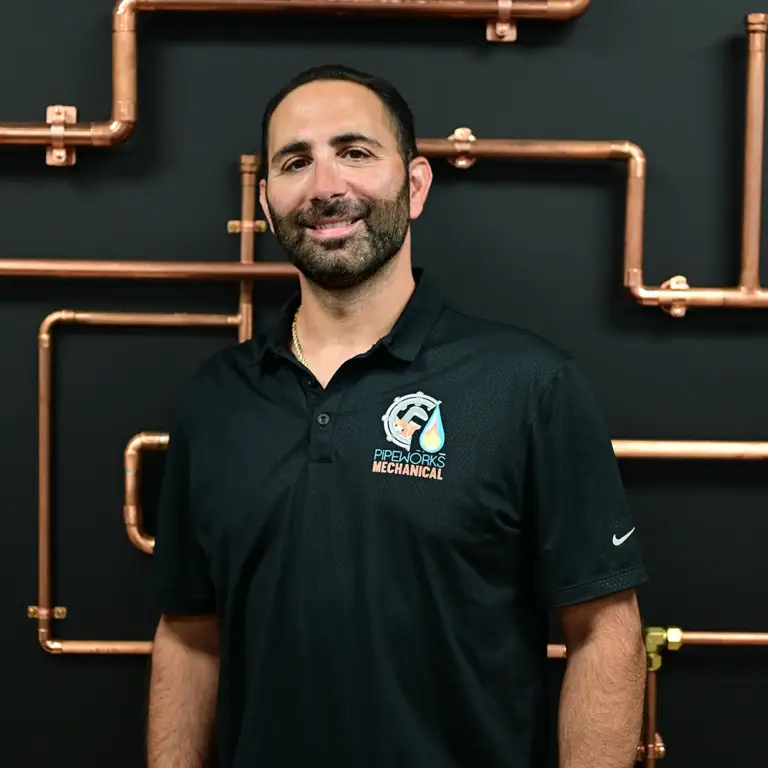 Domenico in a Pipeworks Mechanical polo in front of copper piping